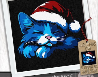 Può includere: Stampa incorniciata di un gatto blu con un cappello di Babbo Natale, su sfondo nero. Il gatto ha gli occhi chiusi e le zampe incrociate. Un'etichetta dice "Christmas Cat" con una piccola immagine del gatto.