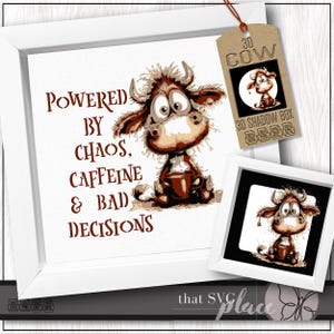 Könnte beinhalten: Ein gerahmter Druck mit einer Cartoon-Kuh-Illustration und dem Text "POWERED BY CHAOS, CAFFEINE & BAD DECISIONS". Ein kleinerer gerahmter Druck und ein Anhänger mit einer Kuhgrafik sind ebenfalls sichtbar. Das Kunstwerk befindet sich in einem weißen Rahmen.