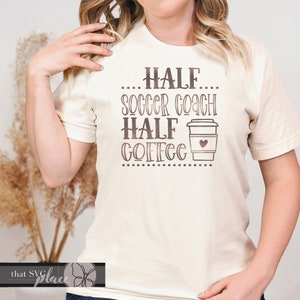 May include: A white t-shirt with a brown graphic that says "...HALF... SOCCER COACH HALF COFFEE..." with a coffee cup graphic.