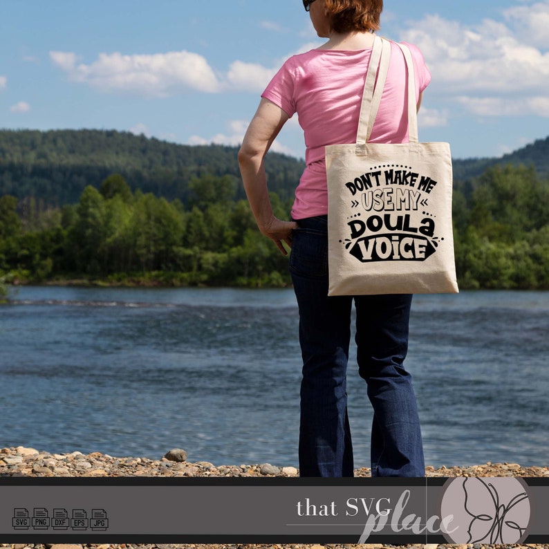 Pu&ograve; includere: Una borsa tote in tela bianca con testo nero che recita "Non farmi usare la mia voce da doula". La borsa viene portata da una persona che indossa una camicia rosa e jeans blu.