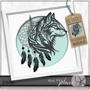 Può includere: Una silhouette di testa di lupo in bianco e nero con un acchiappasogni e piume, all'interno di un cerchio su uno sfondo blu chiaro. Il testo "3D WOLF" è in una scatola marrone con un'immagine più piccola della testa di lupo all'interno.