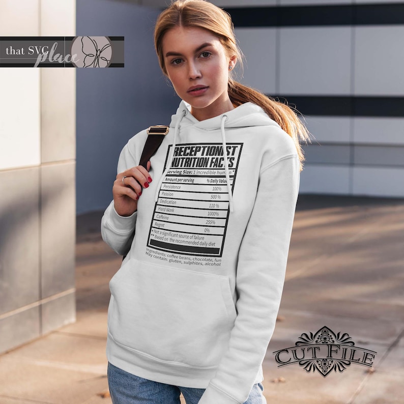 Op de afbeelding: Witte hoodie met een zwarte afbeelding van een voedingsschema met de tekst "Receptionist Nutrition Facts". Het schema somt verschillende eigenschappen op zoals doorzettingsvermogen, passie, toewijding, hard werken, cafe&iuml;ne en spijt, met percentages naast elk.