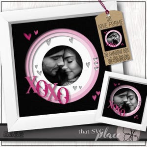Peut inclure: Un cadre blanc avec une boîte d'ombre 3D sur fond noir, présentant une photo d'un couple. Le design comprend des cercles roses, des cœurs et les lettres "XOXO". Une version encadrée plus petite et une étiquette "3D LOVE FRAME" sont également visibles.