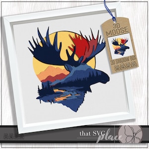 May include: A framed 3D moose art piece. The artwork features a moose silhouette in dark blue, with red antlers, set against a yellow sun and a landscape. A tag reads "3D MOOSE" and "3D SHADOW BOX".