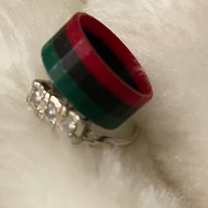 May include: A set of two rings, one is a silver band with clear stones and the other is a red, black, and green silicone band.