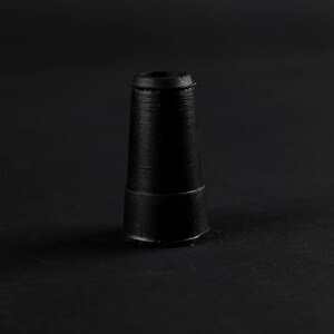 K&ouml;nnte beinhalten: Ein schwarzes, kegelf&ouml;rmiges Objekt aus Gummi mit einer flachen Oberseite und einem leicht erh&ouml;hten Ring in der Mitte.