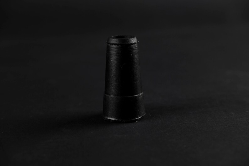 K&ouml;nnte beinhalten: Ein schwarzes, kegelf&ouml;rmiges Objekt aus Gummi mit einer flachen Oberseite und einem leicht erh&ouml;hten Ring in der Mitte.
