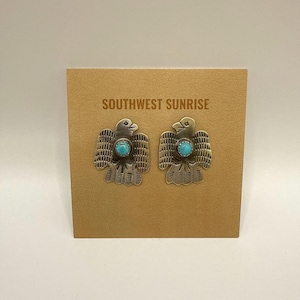 May include: A pair of silver-toned metal earrings in the shape of a bird, each with a turquoise-colored stone in the center. The earrings are displayed on a brown card with the text "SOUTHWEST SUNRISE" printed in brown.