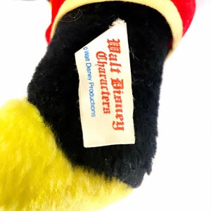May include: Close-up of a black and yellow plush toy with a white tag that reads "Walt Disney Characters" and "&copy; Walt Disney Productions".