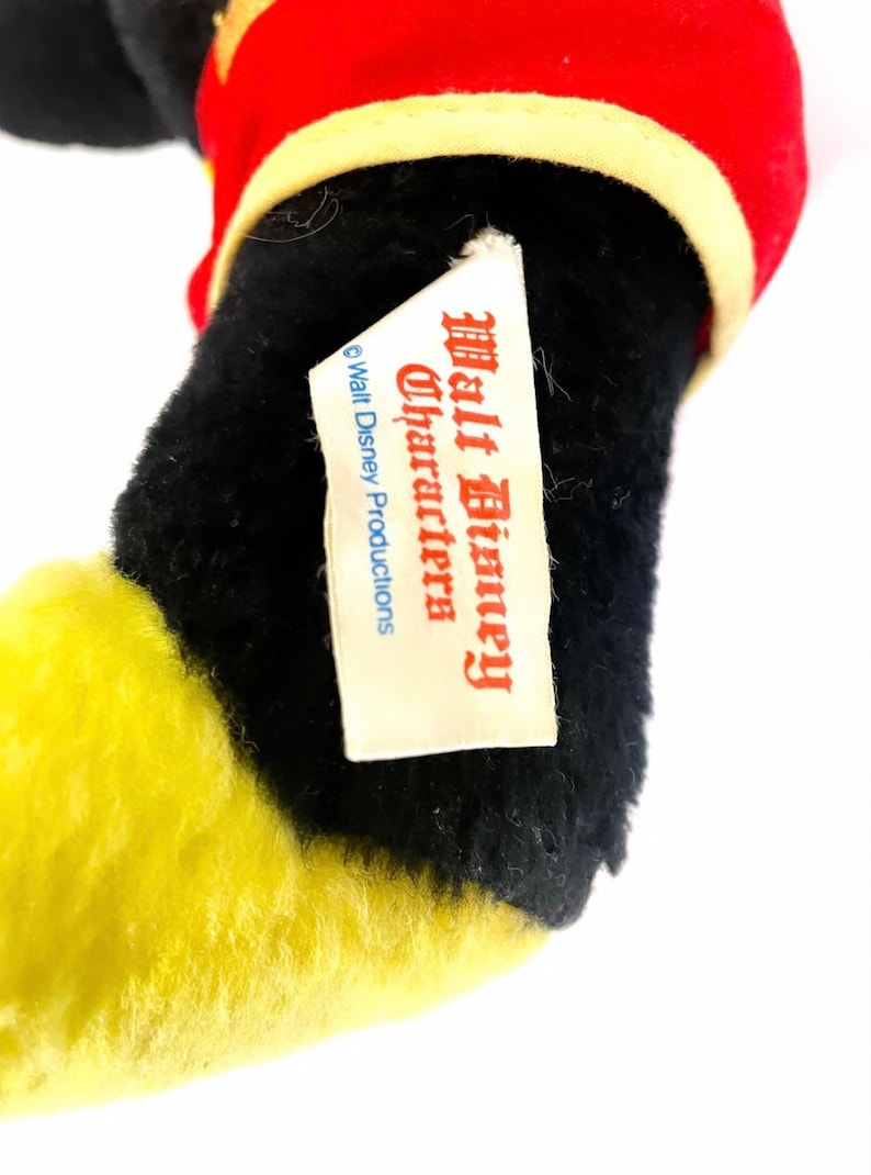 May include: Close-up of a black and yellow plush toy with a white tag that reads "Walt Disney Characters" and "&copy; Walt Disney Productions".
