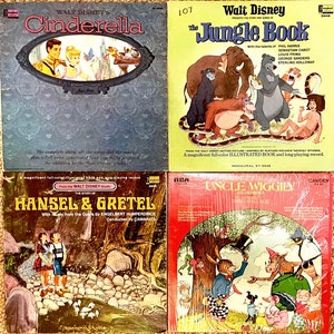 May include: Four vintage record albums featuring classic children's stories. The albums are in their original packaging and feature colourful illustrations of Cinderella, The Jungle Book, Hansel and Gretel, and Uncle Wiggily.