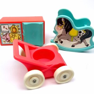 May include: A set of three vintage plastic toys for children. The toys include a red toy stroller, a blue rocking horse, and a red toy dresser with a blue door. The toys are in good condition and have a vintage look.