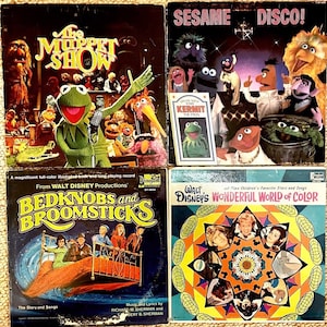 May include: Four vintage vinyl record albums featuring characters from Sesame Street, The Muppet Show, Bedknobs and Broomsticks, and Walt Disney's Wonderful World of Color. The albums are in a colourful, retro style.
