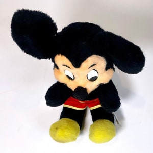 May include: A black plush Mickey Mouse toy with yellow shoes and red shorts. The toy has a classic Mickey Mouse design with large ears and a friendly face.