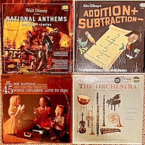May include: Four vintage vinyl records with colourful covers. The top left record features a ship with a red, white and blue flag and the text "Walt Disney presents National Anthems and their stories". The top right record features a cartoon character with a pencil and the text "Walt Disney's Addition + Subtraction - Educational and Entertaining". The bottom left record features three children singing and the text "Bob Hastings 45 Songs Children Love to Sing". The bottom right record features a variety of musical instruments and the text "A Child's Introduction to The Orchestra and All Its Instruments".