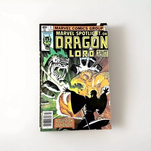 May include: A comic book cover featuring a green dragon with a yellow and orange background. The title of the comic is "Marvel Spotlight on Dragon Lord" and the text "A Question of Honor!" is at the bottom of the cover.