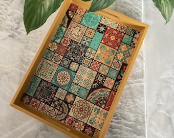 May include: A wooden serving tray with a colorful geometric pattern. The pattern features a variety of shapes and colors, including blue, green, red, and yellow. The tray is perfect for serving snacks, drinks, or other items.