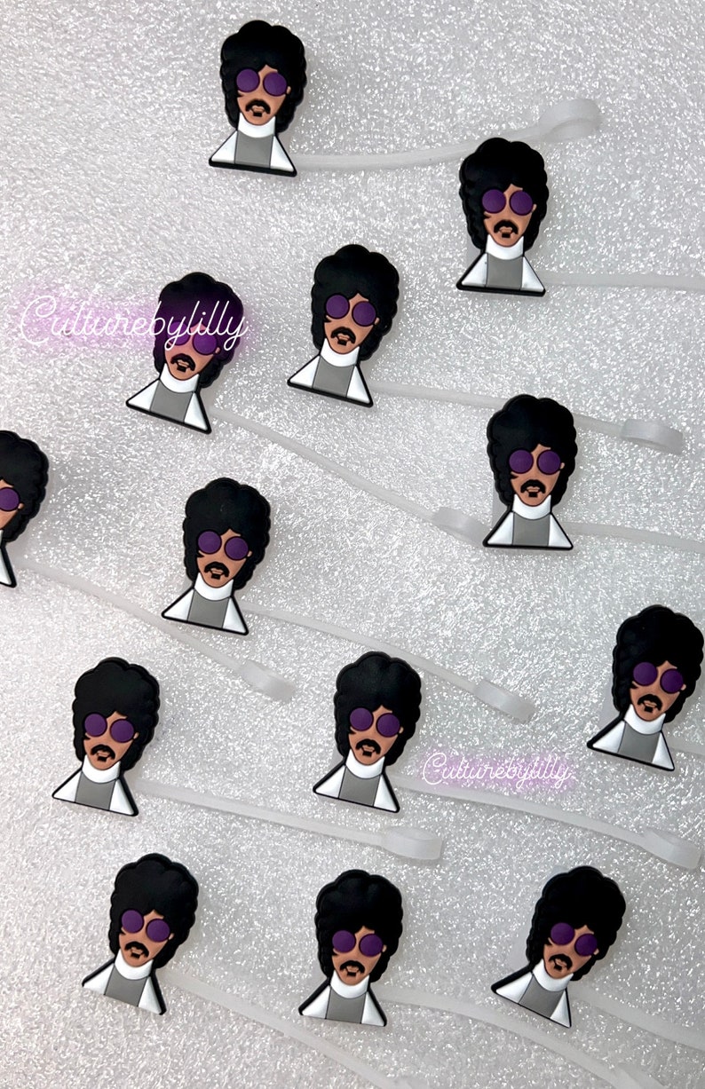May include: A set of 10 purple and black Prince-inspired shoe charms. Each charm features a cartoon image of Prince wearing a purple suit and sunglasses. The charms are attached to clear plastic strings.