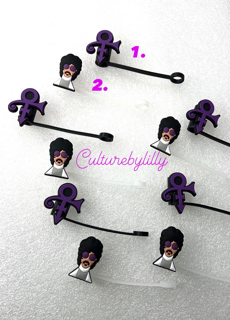 May include: A set of eight purple and black Prince-themed charms. Each charm features a purple symbol and a cartoon image of Prince wearing sunglasses. The charms are attached to black cords with a loop at the end.