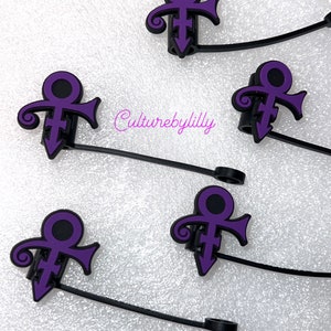 May include: Five purple Prince symbol charms on black elastic bands. The charms are attached to the bands with a small black ring.