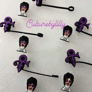 May include: Purple Prince symbol and Prince cartoon face charms on black cord with a silver ring.  The charms are for a phone case or other accessories.  The text "Culturebylilly" is visible in the image.