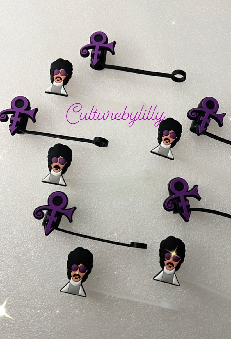 May include: Purple Prince symbol and Prince cartoon face charms on black cord with a silver ring.  The charms are for a phone case or other accessories.  The text "Culturebylilly" is visible in the image.