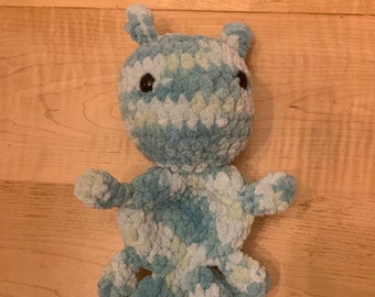 May include: A blue and white crocheted stuffed animal shaped like an ant. The ant has large black eyes and a fuzzy texture.
