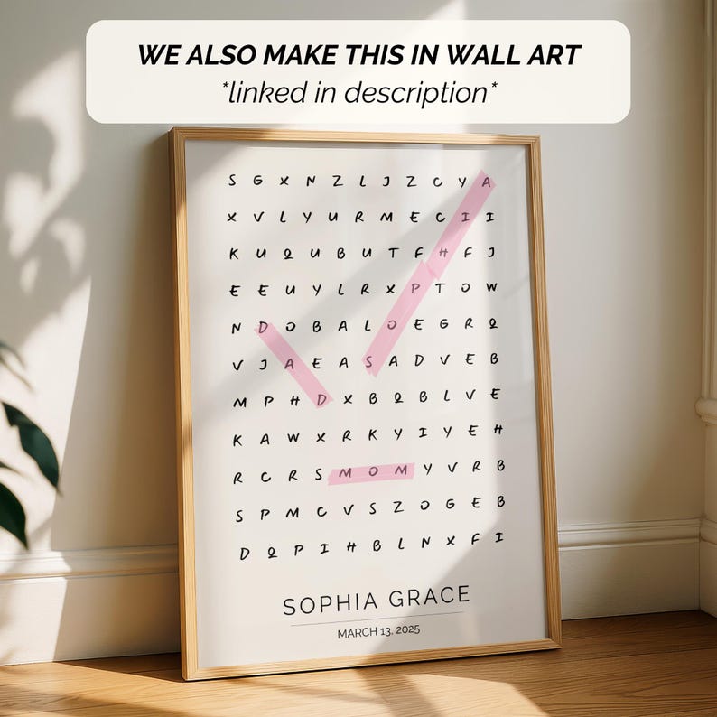May include: A framed word search puzzle with the name "Sophia Grace" and the date "March 13, 2025" at the bottom. The puzzle has a pink check mark highlighting the word "MOMY". The text "WE ALSO MAKE THIS IN WALL ART *linked in description*" is at the top.