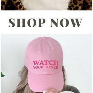 Puede incluir: Imagen promocional para ideas de regalos para estilistas. La imagen presenta una camiseta beige con el texto "I'd Root Tap That", una gorra de b&eacute;isbol rosa con "Watch Your Toner" y una camiseta verde con el mismo texto en la espalda.