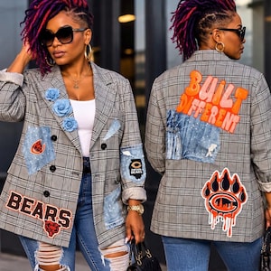 May include: A grey plaid blazer featuring blue denim patches, three blue fabric roses, and Chicago Bears team branding. The back displays the orange text BUILT DIFFERENT above a large orange and black bear claw logo with a city skyline graphic.