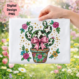 Puede incluir: Un diseño rectangular blanco con un cactus de dibujos animados en una maceta floral, adornado con un lazo rosa. El cactus tiene un patrón en blanco y negro. El diseño está rodeado de rosas rosas, purpurina dorada y el texto "Digital Design PNG".