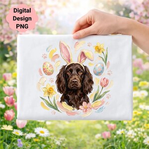 Może przedstawiać: Biały prostokątny wzór przedstawiający brązowego psa w króliczych uszach, otoczonego pisankami, kwiatami i odciskami łap. Słowa "Digital Design PNG" znajdują się w lewym górnym rogu. Wzór jest trzymany przez dłoń.