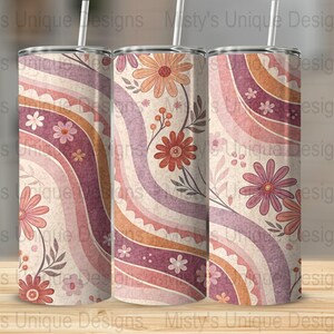 May include: Three stainless steel tumblers with a floral pattern and wavy lines in shades of pink, orange, and brown. The tumblers are on a wooden surface.