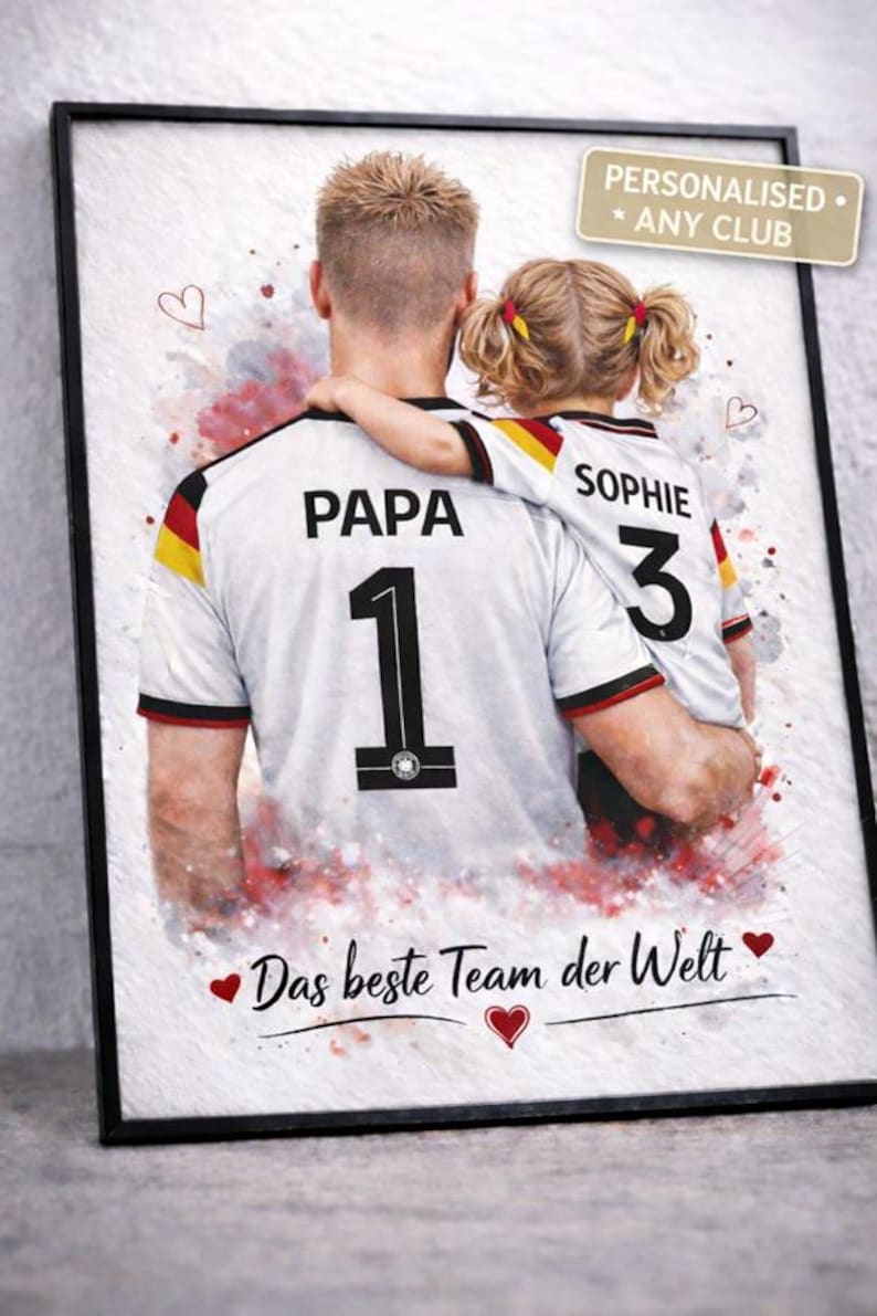 May include: Framed print featuring a father and child in matching soccer jerseys. The father's jersey has "PAPA" and the number "1", while the child's says "SOPHIE" and "3". The print includes the text "Das beste Team der Welt" and "PERSONALISED * ANY CLUB".