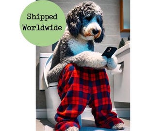 Op de afbeelding: Een hond met grijs en wit haar, gekleed in een rood-blauwe geruite pyjamabroek, zit op een toilet en kijkt naar een smartphone. De tekst "Shipped Worldwide" staat in een groene cirkel.
