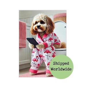 May include: A dog wearing flamingo-print pajamas and holding a smartphone. The white pajamas have pink trim and feature a repeating pattern of pink flamingos. The dog is sitting on a toilet in a bathroom setting.