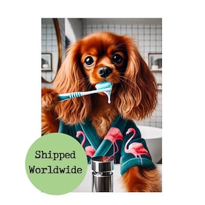 May include: A brown and white Cavalier King Charles Spaniel dog wearing a teal blue robe with pink flamingo print is brushing its teeth with a blue toothbrush and toothpaste.