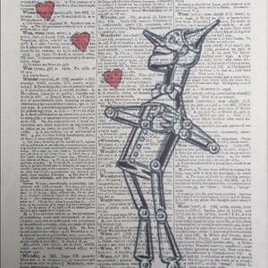Pu&ograve; includere: Un'illustrazione in bianco e nero dell'Omino di Latta del Mago di Oz, in piedi su una pagina di un dizionario vintage. La pagina del dizionario presenta le definizioni delle parole "Wombat", "Wonder" e "Wood".