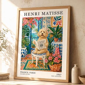 Puede incluir: Una lámina enmarcada titulada HENRI MATISSE que muestra a un perro golden doodle sentado en un taburete blanco leyendo un periódico titulado LE JOURNAL DES ARTS. La escena representa un interior colorido con plantas y azulejos azules.