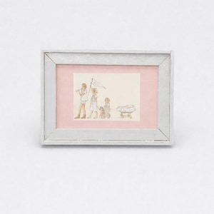 May include: A framed watercolour print showing a children's procession. The artwork depicts three children, one carrying a flag, and another pulling a small table. The frame is white with a distressed finish, and the background is a soft pink.