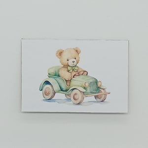 Op de afbeelding: Waterverfillustratie van een teddybeer die in een vintage groene auto rijdt. De beer draagt een groene vlinderdas en zit achter het stuur. De auto heeft crèmekleurige wielen en een groen interieur. Het kunstwerk staat op een witte achtergrond.