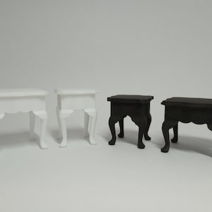 May include: Four miniature tables, two white and two black, with a simple design and four legs. The tables are made of wood and have a smooth finish.