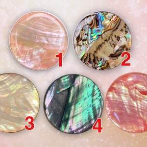 May include: Five round iridescent shell phone grips numbered 1 to 5. The grips are in various colours including pink, green, and brown.