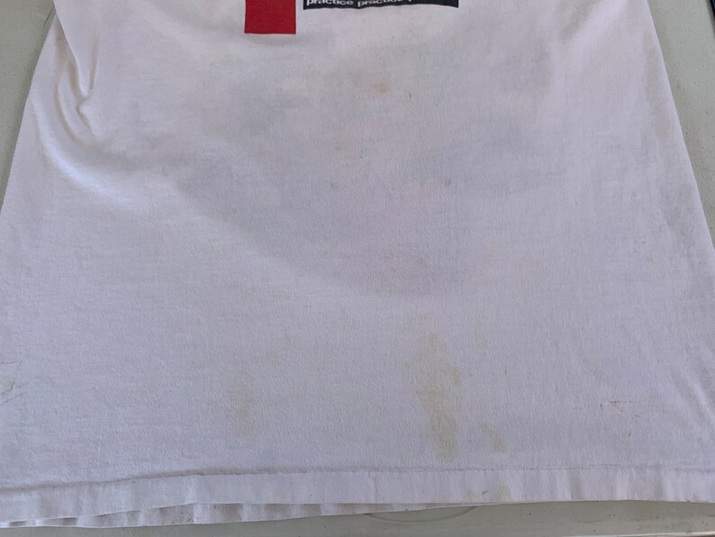 May include: White t-shirt with a red rectangle and the text "practice practice" on the top.
