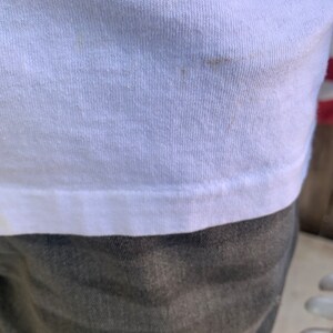 May include: White t-shirt with a slight brown stain.