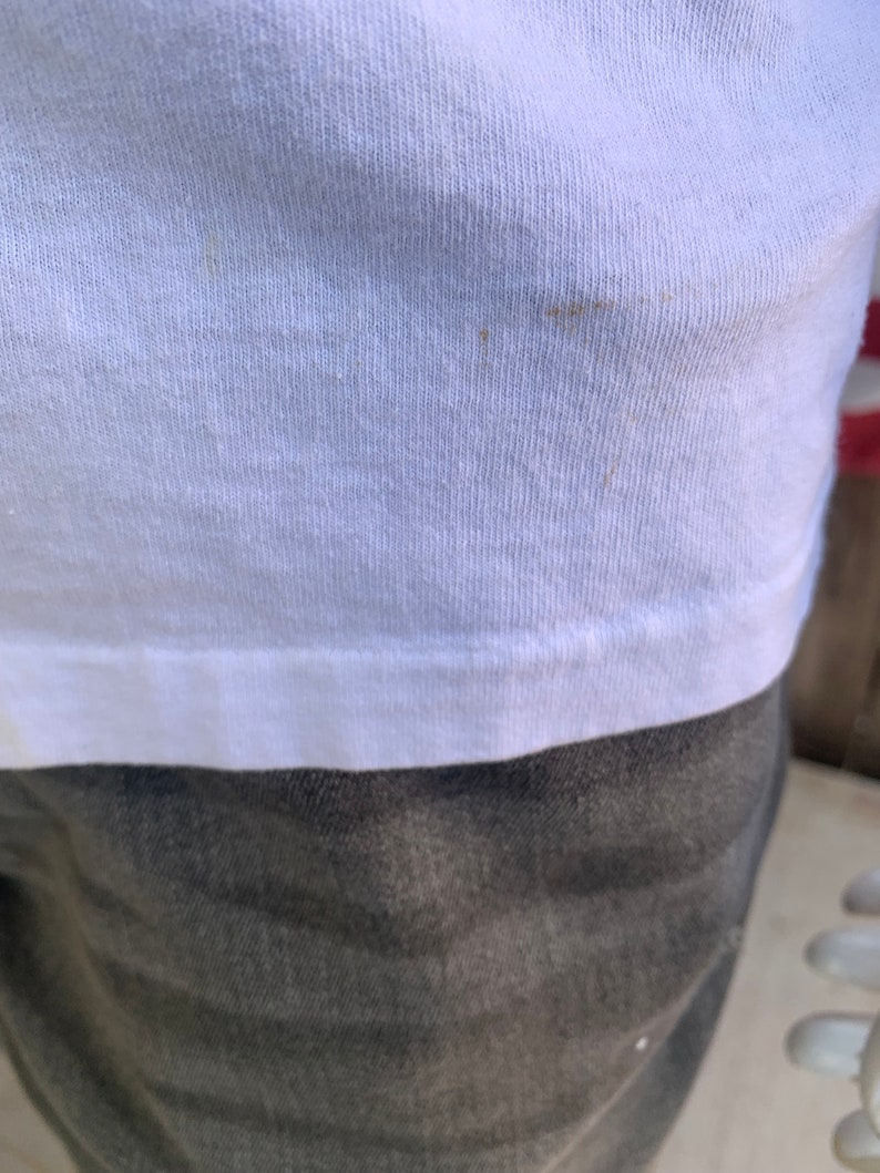 May include: White t-shirt with a slight brown stain.