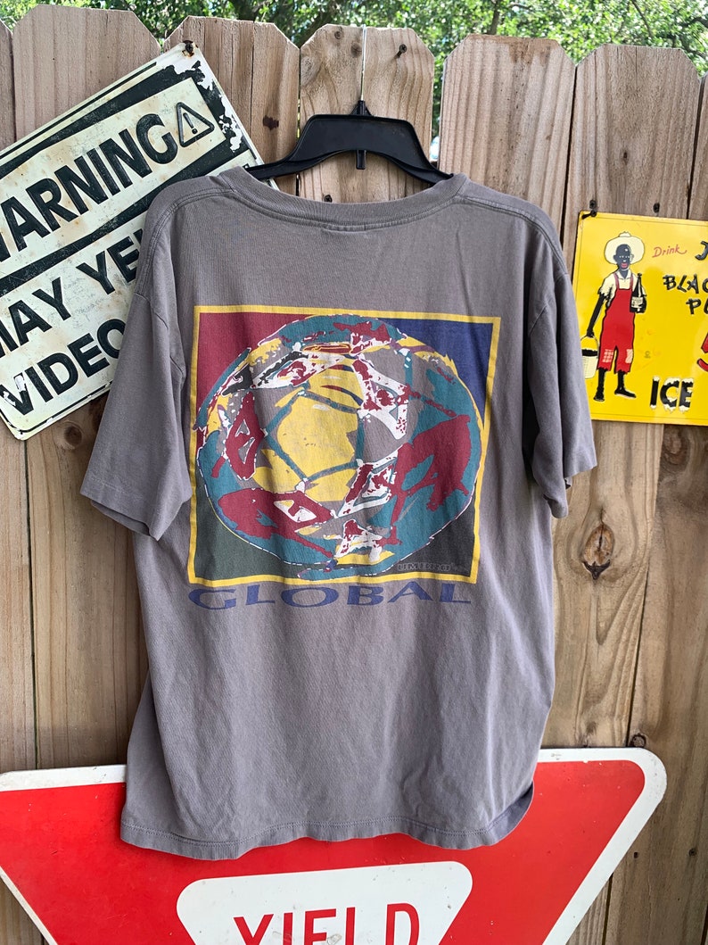 May include: Grey t-shirt with a graphic of a colourful globe and the word "GLOBAL" printed on the back.