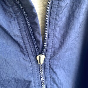 May include: A navy blue zipper on a jacket. The zipper is metal and has a silver finish.