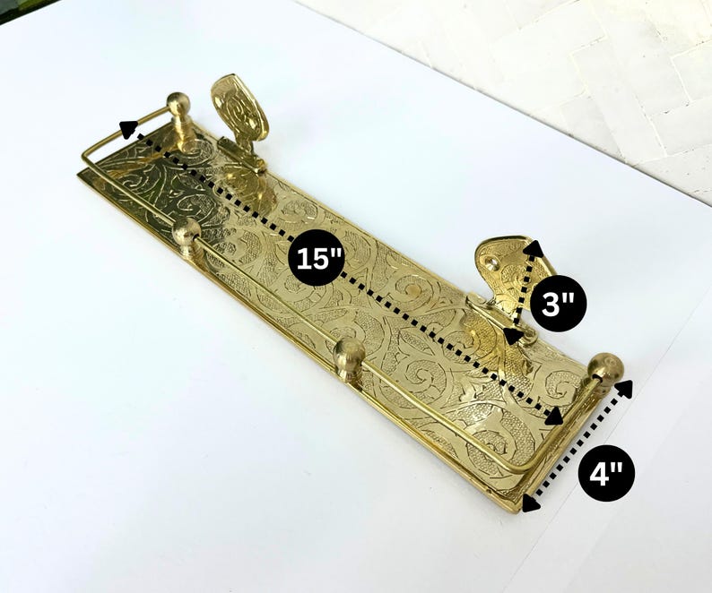 Puede incluir: Un estante de metal dorado con un dise&ntilde;o floral ornamentado. El estante mide 38 cm de largo, 10 cm de ancho y 8 cm de alto. Tiene dos soportes decorativos y detalles en forma de bola. El estante est&aacute; dise&ntilde;ado para montarse en la pared.