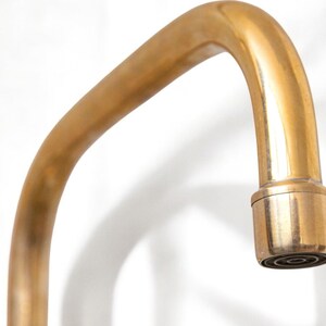 May include: A gold-toned faucet with a curved spout and a round, aerated nozzle.